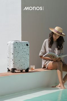 a woman sitting next to a pool reading a book