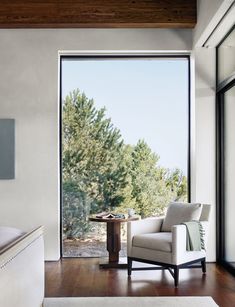 a white chair sitting in front of a large window on top of a hard wood floor