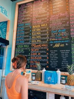 a woman standing in front of a menu on a chalkboard with pineapples