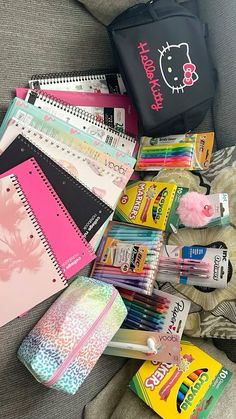 many school supplies are laid out on the couch next to a book and pencils