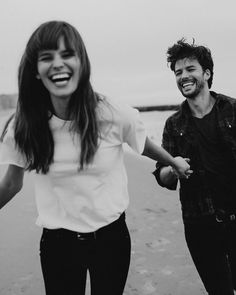 black and white photo of two people walking on the beach holding hands with each other