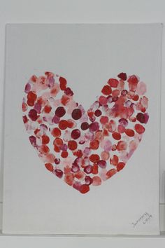 a heart made out of red and pink circles on a white paper with a marker next to it