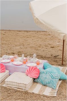 a picnic set up on the beach with an umbrella