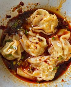 a white bowl filled with dumplings covered in sauce