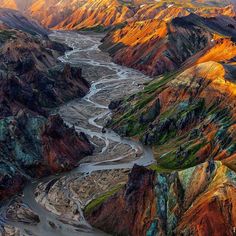 an aerial view of mountains and rivers in the land with green, orange, yellow and blue colors