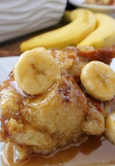 some bananas and syrup are on a plate with other food items in the back ground