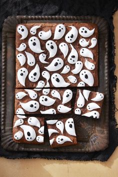 halloween treats are decorated with white icing and spooky ghost faces on brown paper