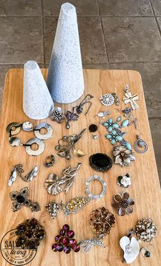 a table topped with lots of jewelry on top of a wooden cutting board next to a vase