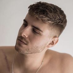 a shirtless man with ear buds in his ears looking off to the side while wearing a necklace