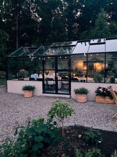 an outdoor dining area with potted plants and lights in the windows, surrounded by gravel