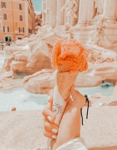 a person holding an ice cream cone in front of the parthenion, rome