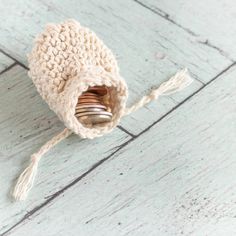 a small crocheted bag with coins in it sitting on a wooden floor next to a string