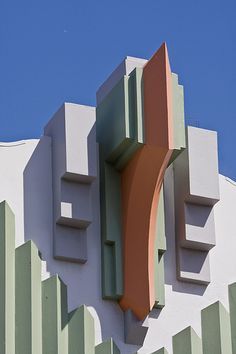 a clock on the side of a building that is painted white and green with orange accents