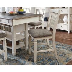 a kitchen table with two chairs and a rug on the floor in front of it