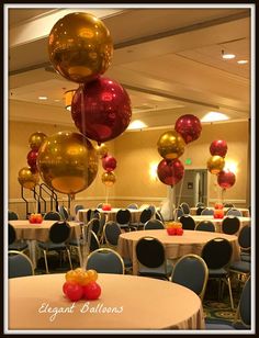 several balloons are hanging from the ceiling in a banquet room with round tables and chairs