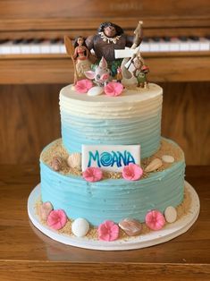 there is a blue cake with pink flowers on the bottom and an animal figurine on top