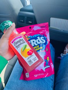 a person sitting in the back seat of a car holding a bag of fruit juice