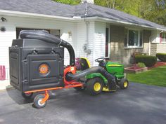 a lawn mower parked in front of a house with a cart attached to it