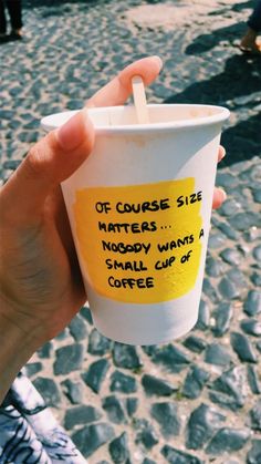 a person holding up a cup with writing on it