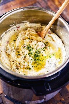 mashed potatoes in an electric pressure cooker with a wooden spoon sticking out of the top