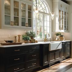 a kitchen with an arched window, sink and cabinets in the center is white and black