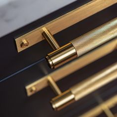 a close up of a metal handle on a black and gold drawer with brass handles