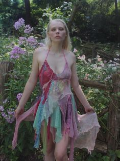 a woman with blonde hair wearing a pink and green dress standing in front of flowers