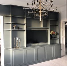 an entertainment center with built - in shelving and chandelier