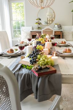 a dining room table with candles, grapes and other food on it's placemats