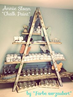 a wooden shelf with jars and candles on it in front of a wall painted blue