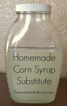 a glass jar filled with corn syrup on top of a wooden table next to a wall