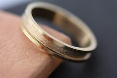 a wedding ring sitting on top of a piece of paper next to a wooden block