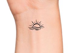 the sun is shining above the water on this wrist tattoo design for women and men