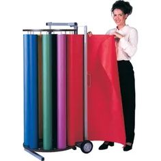 a woman standing next to a cart with various colored sheets on it and holding onto the cover