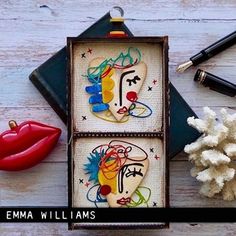 two cross stitch kits in a box with red lips and other items on the table