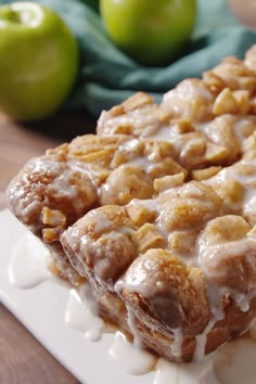 a close up of a piece of cake on a plate with apples in the background