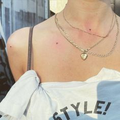 a close up of a person wearing a white shirt with a heart necklace on it