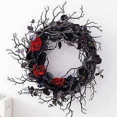 there is a wreath with red roses and branches on the wall next to an electrical outlet