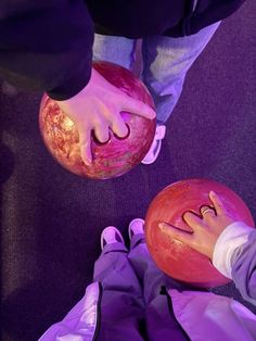 two people holding bowling balls in their hands