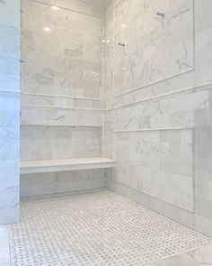 a walk in shower sitting next to a white tiled wall with shelves on each side