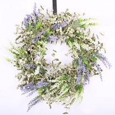 a wreath with lavenders and green leaves hanging on a wall