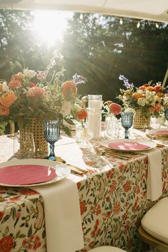 Bright Table Settings with a Floral Printed Linens and Colored Glassware Floral Table Cloth Decor, Tablecloth Wedding Ideas, Garden Party Table Scape, Patterned Table Cloth Wedding, Pattern Table Cloth Wedding, Round Table Tablescapes, Colorful Wedding Tablescape, Round Table Scape, Pattern Tablecloth Wedding