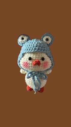 a crocheted stuffed animal wearing a blue hat and scarf hanging from a hook