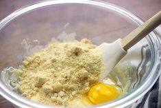 an egg and flour in a bowl with a wooden spoon