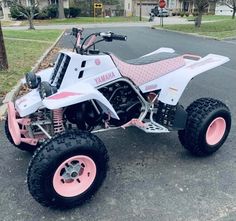 a pink and white atv is parked on the street