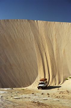 a van is parked in front of a large sand dune