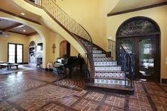 a large foyer with stairs and tile flooring next to a piano in the center