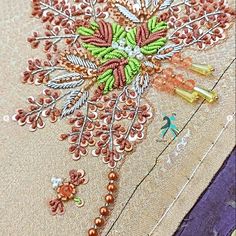 a close up view of an embroidered fabric with beading and flowers on the side