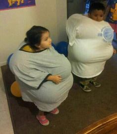 two young children standing in front of a mirror with giant pillows on their heads and arms