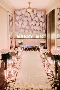 a long table with candles and flowers on it in front of a large sign that says marry me